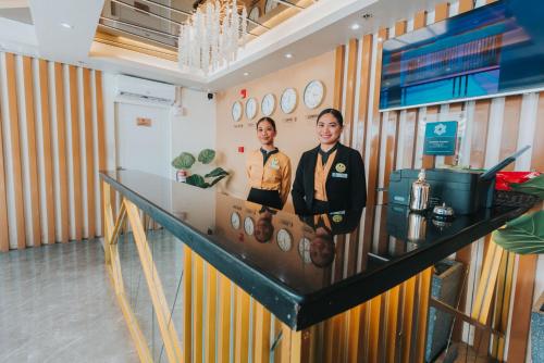 two people standing behind a counter in a room at SureStay Studio by Best Western Clarkview Angeles City in Angeles