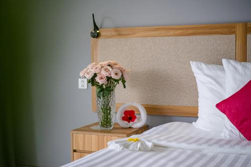 a vase of flowers on a table next to a bed at Mercury Phu Quoc Resort & Villas in Phu Quoc