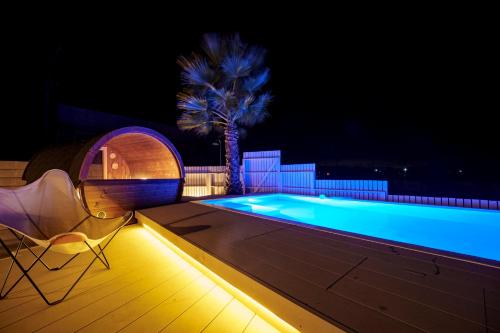 a pool with a chair and a palm tree at night at UMInoTERRACE in Minamiboso