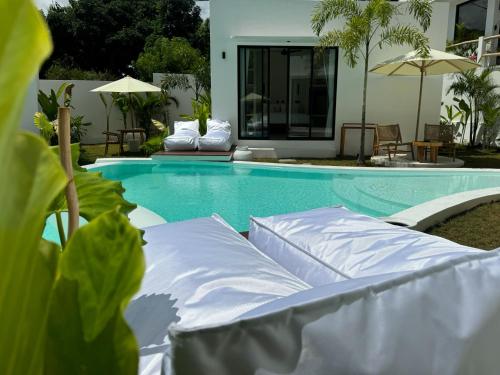 a swimming pool with chairs and umbrellas next to a house at Ôkeanos Boutique Hotel - Uluwatu Ungasan in Uluwatu