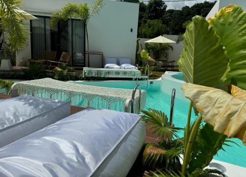 a swimming pool with two pillows and a patio with plants at Ôkeanos Boutique Hotel - Uluwatu Ungasan in Uluwatu