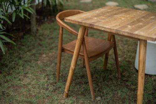 a wooden table with a wooden chair next to it at Ôkeanos Boutique Hotel - Uluwatu Ungasan in Uluwatu