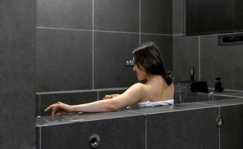 a man in a bath tub in a bathroom at Aank Ryokan Hotel Jeonju in Jeonju