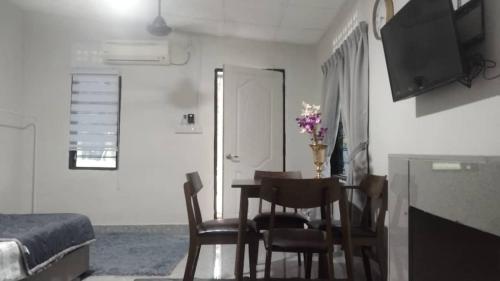 a room with a table and chairs and a bedroom at D'Orkid Homestay Kebun baru in Teluk Panglima Garang
