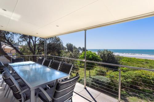 a balcony with a table and chairs and the ocean at Tidemark - Diamond Beach in Diamond Beach