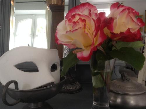 a vase with flowers and a mask on a table at Lamaison du phare honfleur chambres d'hotes et jacuzzi privé in Honfleur