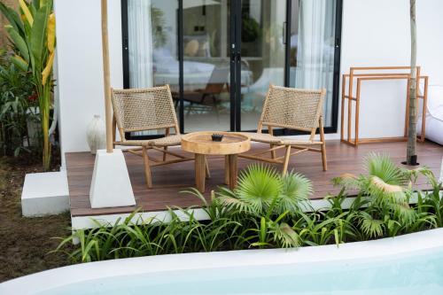 two chairs and a coffee table on a deck at Ôkeanos Boutique Hotel - Uluwatu Ungasan in Uluwatu