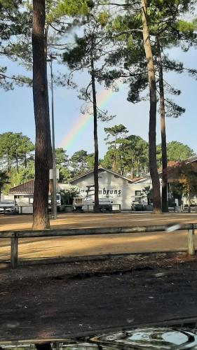 un parc arboré et un bâtiment avec arc-en-ciel dans l'établissement Mobilhome Mobil home Cap ferret, à Claouey