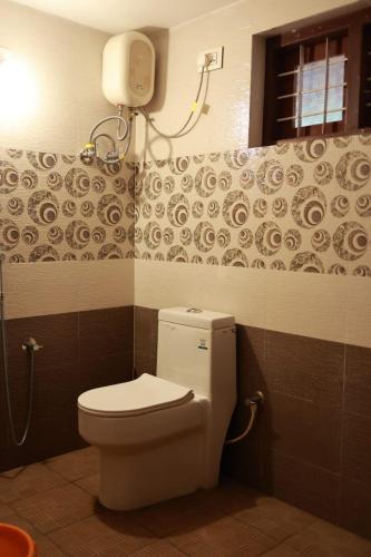 a bathroom with a toilet and a phone on the wall at Blizzard Pool Villa in Padinjarathara