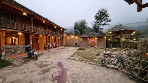 a woman in a pink hijab standing in front of a building at Long Cổ Trấn Homestay in Dồng Văn