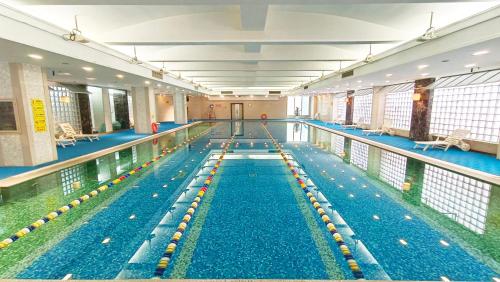 a large swimming pool with blue water in a building at Asia Hotel Beijing in Beijing