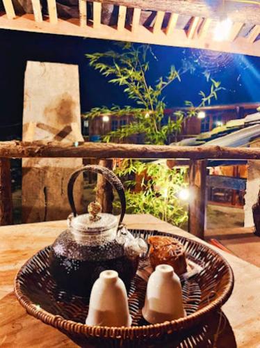a basket with eggs and a tea kettle on a table at Long Cổ Trấn Homestay in Dồng Văn