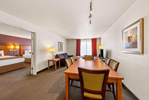 a room with a dining table and a bedroom at Wingate by Wyndham Calgary South in Calgary