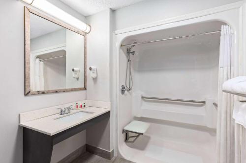 a white bathroom with a sink and a mirror at Baymont by Wyndham Selma in Selma
