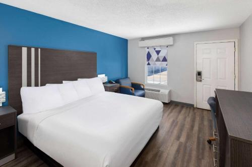 a large white bed in a room with a blue wall at Baymont by Wyndham Selma in Selma
