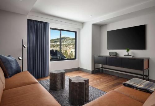 a living room with a couch and a flat screen tv at Hotel Alpenrock Breckenridge, Curio Collection by Hilton in Breckenridge