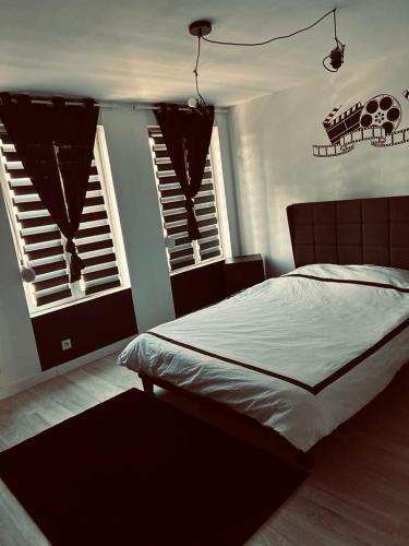une chambre avec un grand lit et deux fenêtres dans l'établissement Maison avec salle cinéma privée, à Berlaimont