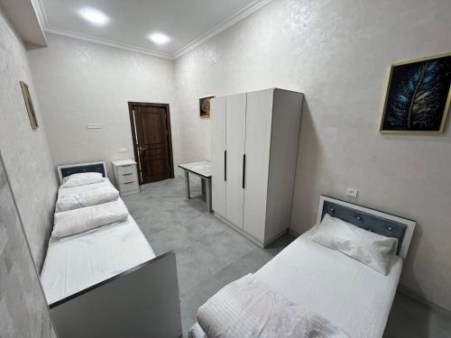 a room with three beds and a desk in it at Hostel Art Sergeli in Stantsiya Kyzyl-Tukumachi