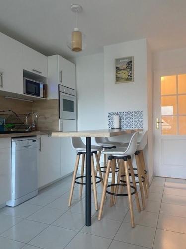 une cuisine avec un comptoir et des tabourets. dans l'établissement Appartement à 400m de la plage - 6 couchages, à Neufchâtel-Hardelot