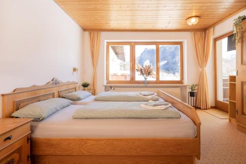 a bedroom with two beds and a window at Zum Hüttenklaus - 12 Personen Gruppenunterkunft in den Bergen mit eigenem Badezuber in Bad Hindelang