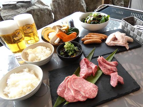 a table with meat and other foods and a beer at Biwa-Lakeside Cottage B B Dylan in Minami-komatsu