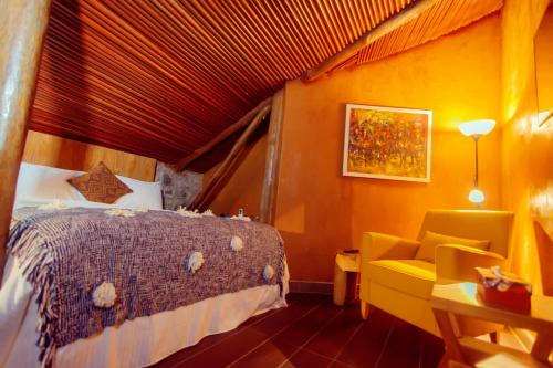 a bedroom with a bed and a yellow chair at Trois Ore Residences & Green Earth Bistro in Ibadan