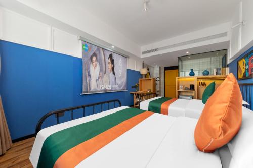 a bedroom with two beds and blue walls at Happy Inn-Xinzheng International Airport Branch喜鹊愉家连锁酒店-机场店 in Zhangzhuangjie