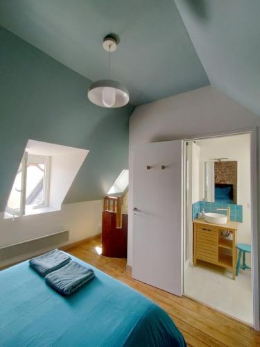 - une chambre avec un lit bleu et un lavabo dans l'établissement Maison de pêcheur en bord de mer, à Grandcamp-Maisy
