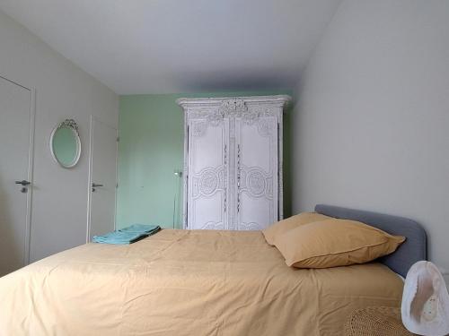a bedroom with a bed and a white cabinet at Maison de pêcheur en bord de mer in Grandcamp-Maisy