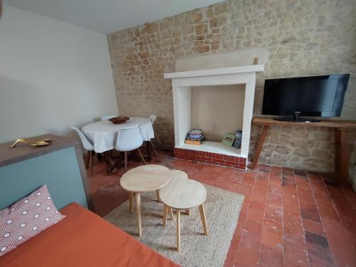 a living room with a fireplace and a table and chairs at Maison de pêcheur en bord de mer in Grandcamp-Maisy
