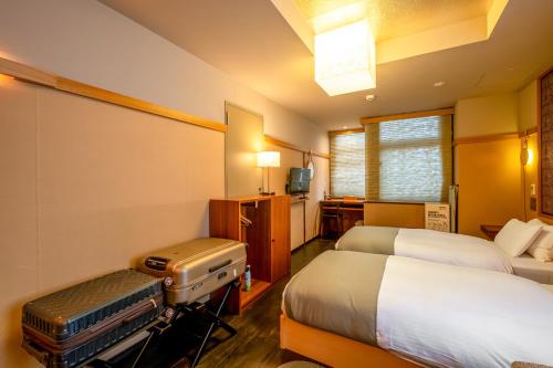 a hotel room with two beds and a suitcase at GOZAN HOTEL & SERVICED APARTMENT Higashiyama Sanjo in Kyoto