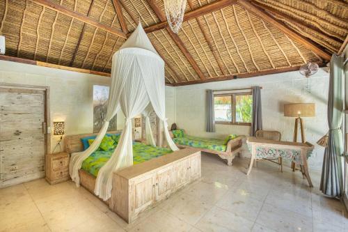 a bedroom with a canopy bed and a desk at Megalan Villa Balangan in Badung