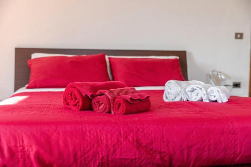 a red bed with red sheets and towels on it at Cappuccini apartment superior in Oristano