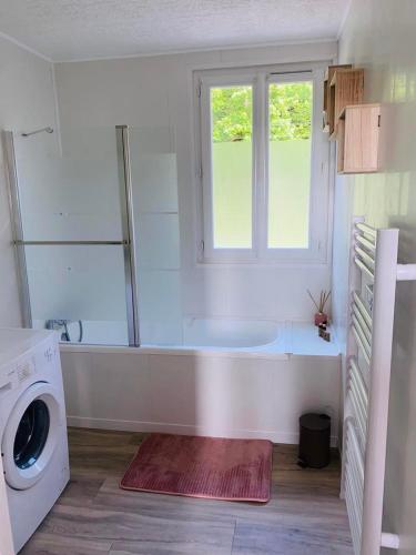 La salle de bains est pourvue d'une baignoire, d'une fenêtre et d'un lave-linge. dans l'établissement Gîtes Le Chêne Pommier, à Fatouville-Grestain