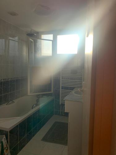 une salle de bain avec une baignoire, un lavabo et une fenêtre dans l'établissement Maison 6 personnes jardin clos et coin terrasse, à Coulommiers