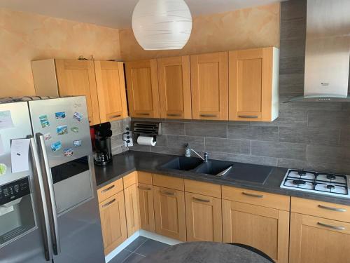 une cuisine avec des armoires en bois et un évier dans l'établissement Maison 6 personnes jardin clos et coin terrasse, à Coulommiers