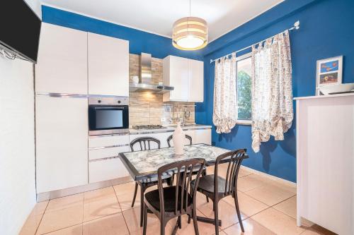 a kitchen with blue walls and a table and chairs at Morgana Holiday Home in Fontane Bianche