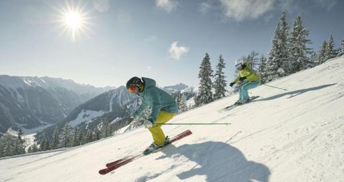 two people are skiing down a snow covered slope at Appartements Naturnah in Schladming