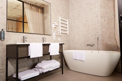 a bathroom with a tub and a sink and towels at Air Hotel in Karmėlava