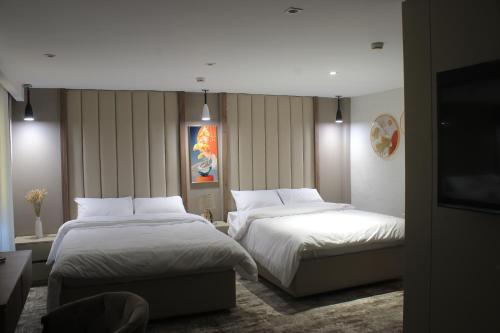 a hotel room with two beds and a flat screen tv at Azmal Hotel & Suites in Irbid