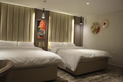 two beds in a hotel room with white sheets at Azmal Hotel & Suites in Irbid