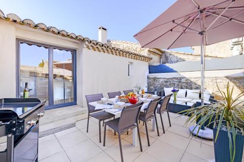 un patio avec une table, des chaises et un parasol dans l'établissement Le Louzoane, à Maussane-les-Alpilles