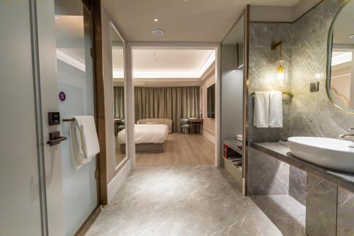 a bathroom with a sink and a bed in a room at Mercure Xichang in Xichang