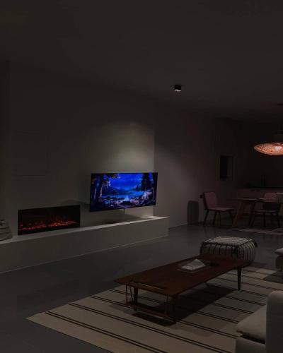 a living room with a couch and a tv on the wall at The Valley Villas in Sharīyah