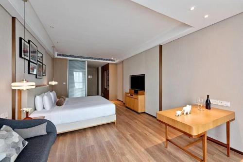 a bedroom with a bed and a table and a couch at OneJasper Qingyue Hotel in Chongqing