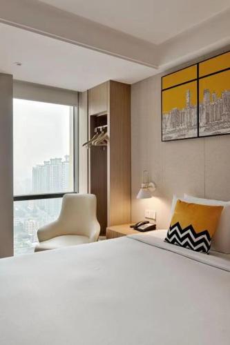 a bedroom with a bed and a chair and a window at OneJasper Qingyue Hotel in Chongqing