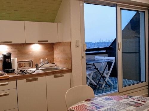 una cucina con lavandino e vista su un balcone di Sea Bird parking draps fournis piscine partagée ad Arzon