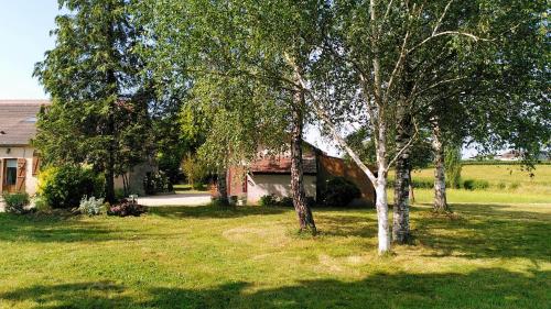 une maison avec des arbres devant une cour dans l'établissement Gîte Le Nid aux Papillons, à Palinges