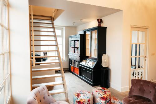 a living room with a staircase and a book shelf at B&B Anna-Grace in Diksmuide