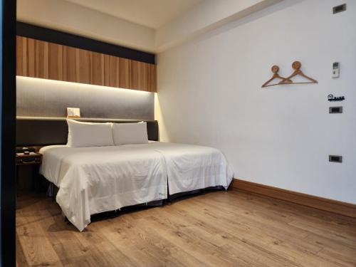 a bedroom with a bed with white sheets and wooden floors at Grange Inn in Taitung City